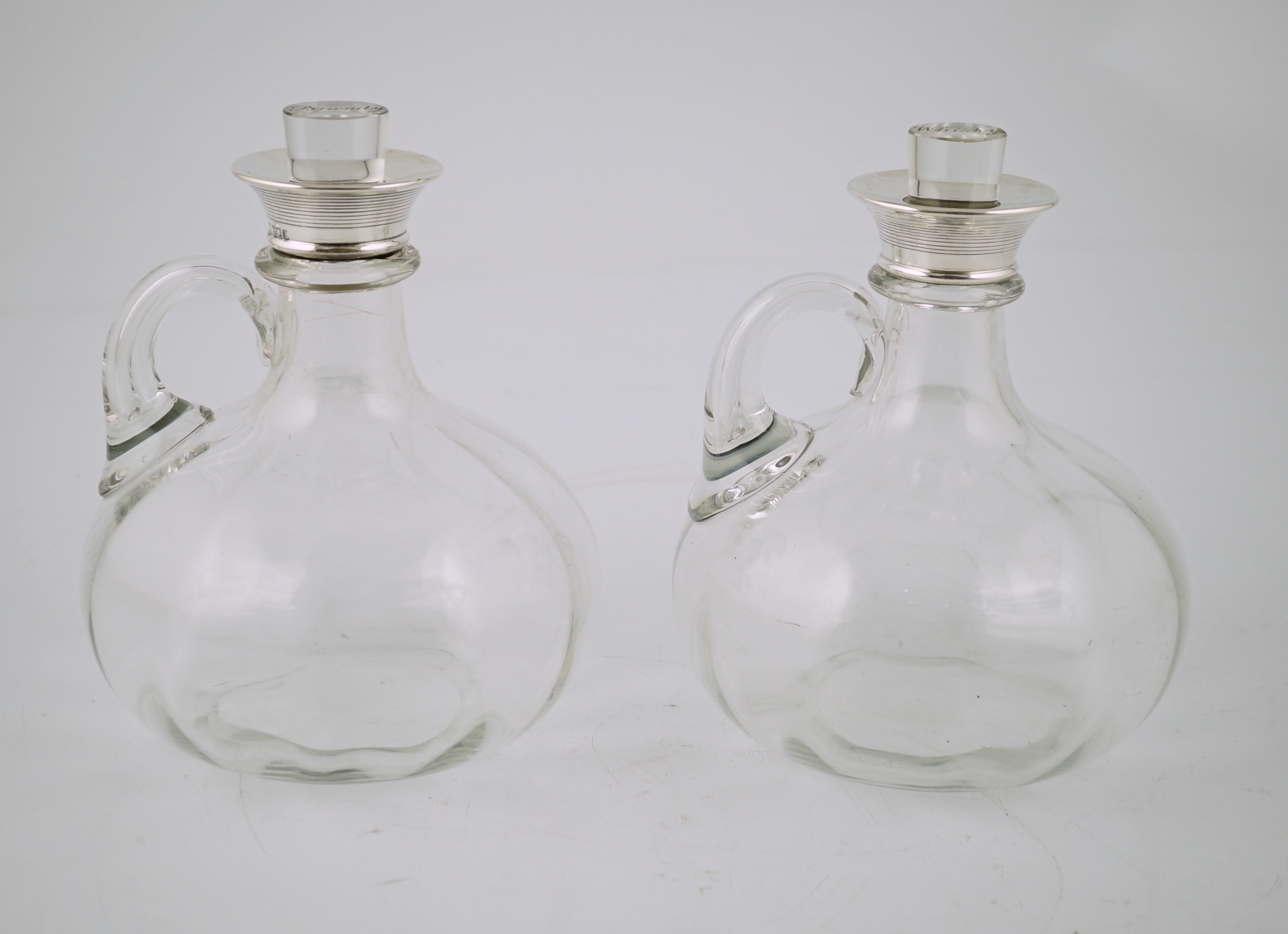 A pair of Edwardian silver mounted glass decanters, with stoppers etched 'Whisky' & 'Brandy', by Charles & George Asprey